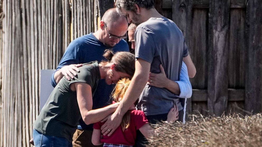PHOTO: A group prays with a child outside the reunification center at the Woodmont Baptist church after a school shooting, Mar. 27, 2023, in Nashville, Tenn.