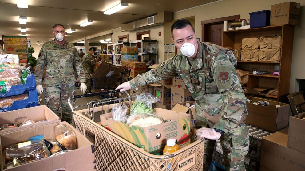 PHOTO: Chief Allan Lawson, right, and Col. Gent Welsh, both from the Washington Air National Guard, help distribute food at the Nourish Pierce County food bank set up at the Mountain View Lutheran Church on April 4, 2020 in Edgewood, Washington. 