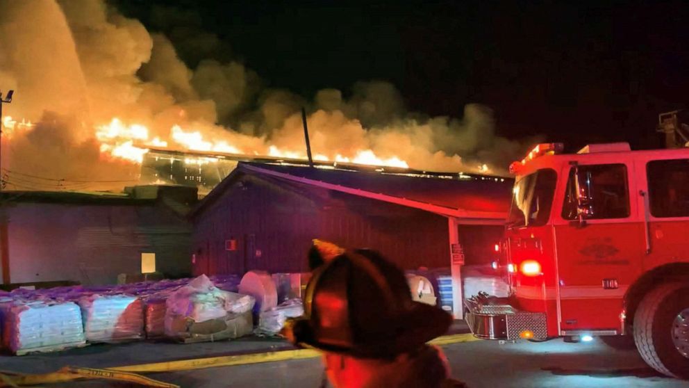 PHOTO: A firefighter walks past a fire engine as Weaver Fertilizer Plant burns on Cherry Street in Winston-Salem, N.C., Jan. 31, 2022.