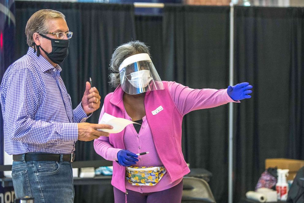 PHOTO: A poll worker assists a voter at the Spectrum Center, during the first day of early voting in Charlotte, N.C., on Oct. 15, 2020.