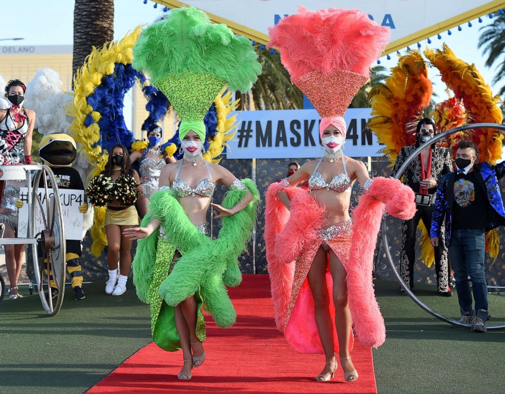 PHOTO: Showgirls participate in a fashion show in front of the Welcome to Fabulous Las Vegas sign to kick off the pro-mask wearing campaign "Mask Up for Nevada," June 25, 2020, in Las Vegas.