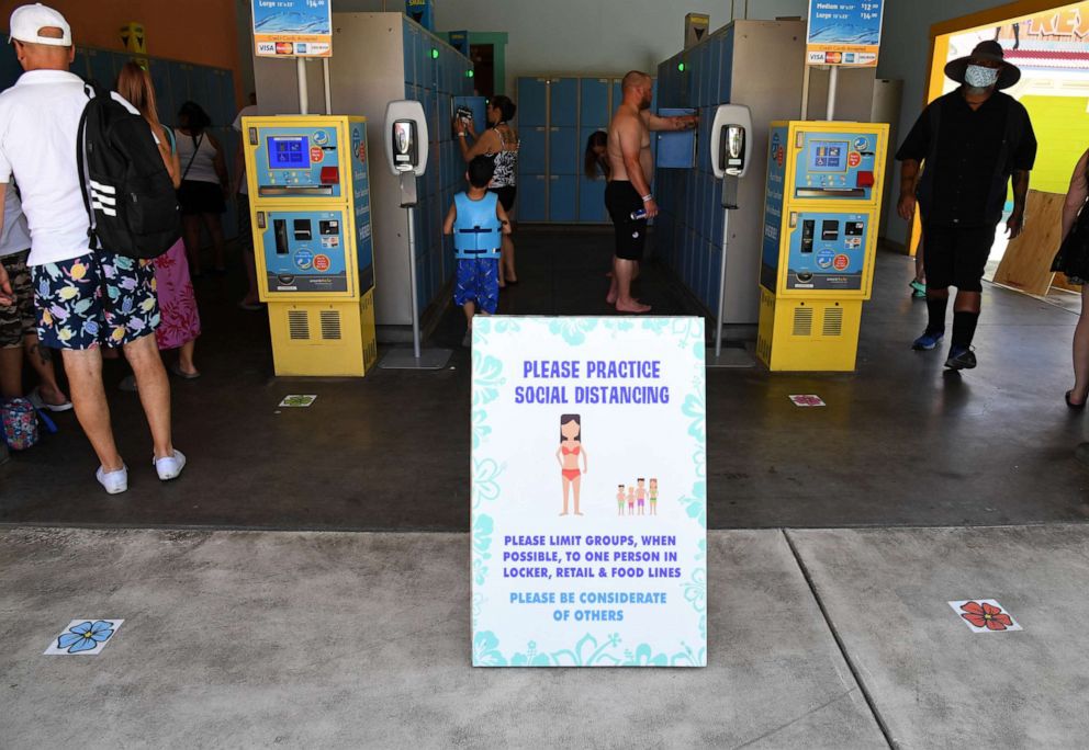 PHOTO: A sign asking guests to practice social distancing is posted outside a locker area at Cowabunga Bay Water Park, which was allowed to open for the first time this weekend because of the coronavirus pandemic on May 30, 2020 in Henderson, Nev. 