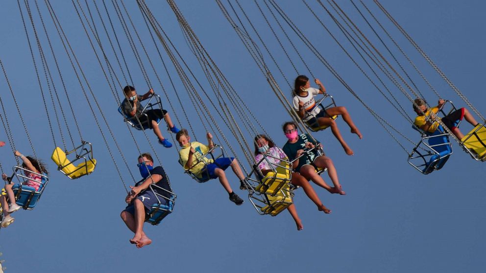PHOTO: People wearing masks ride attractions at an amusement pier on July 3, 2020, in Wildwood, N.J.