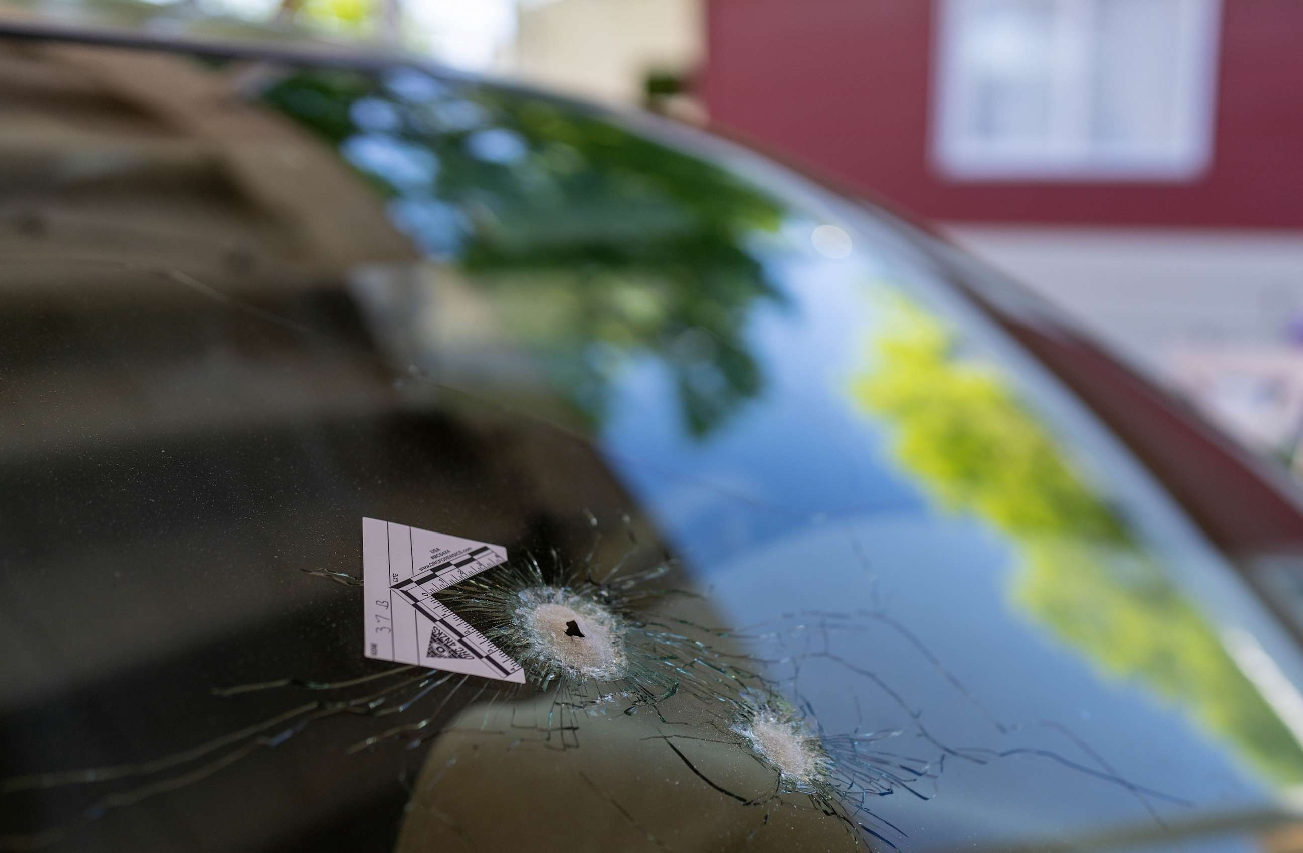 PHOTO: A bullet hole with an evidence marker, which went through a rear window of a car parked across the street where a gunman was shooting at random people on N Dustin Avenue on May 16, 2023 in Farmington, N.M.