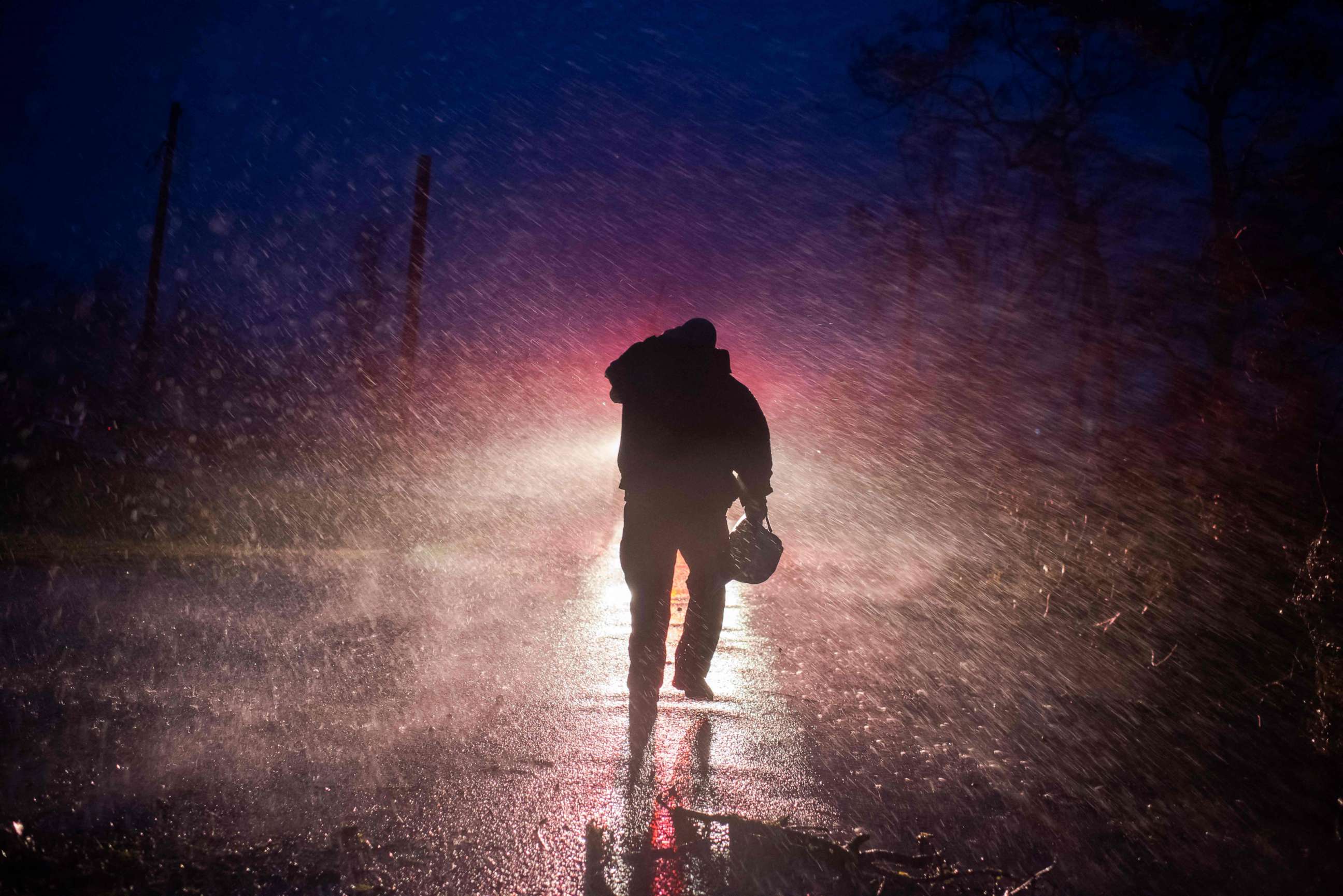 PHOTO: Montegut fire chief Toby Henry walks back to his fire truck in the rain as firefighters cut through trees on the road in Bourg, Louisiana as Hurricane Ida passes on August 29, 2021. 