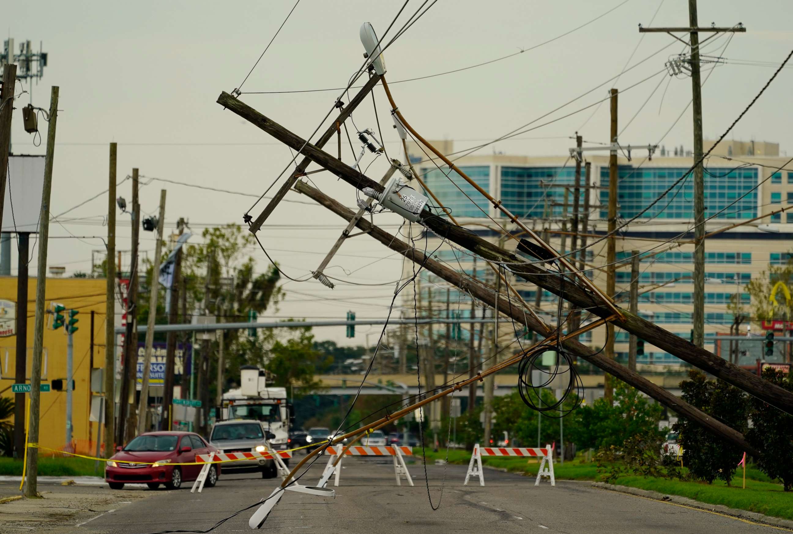 PHOTO: Vehicles are diverted around utility poles damaged by the effects of Hurricane Ida, Tuesday, Aug. 31, 2021, in New Orleans. New Orleans is without power, which may last for several weeks. 