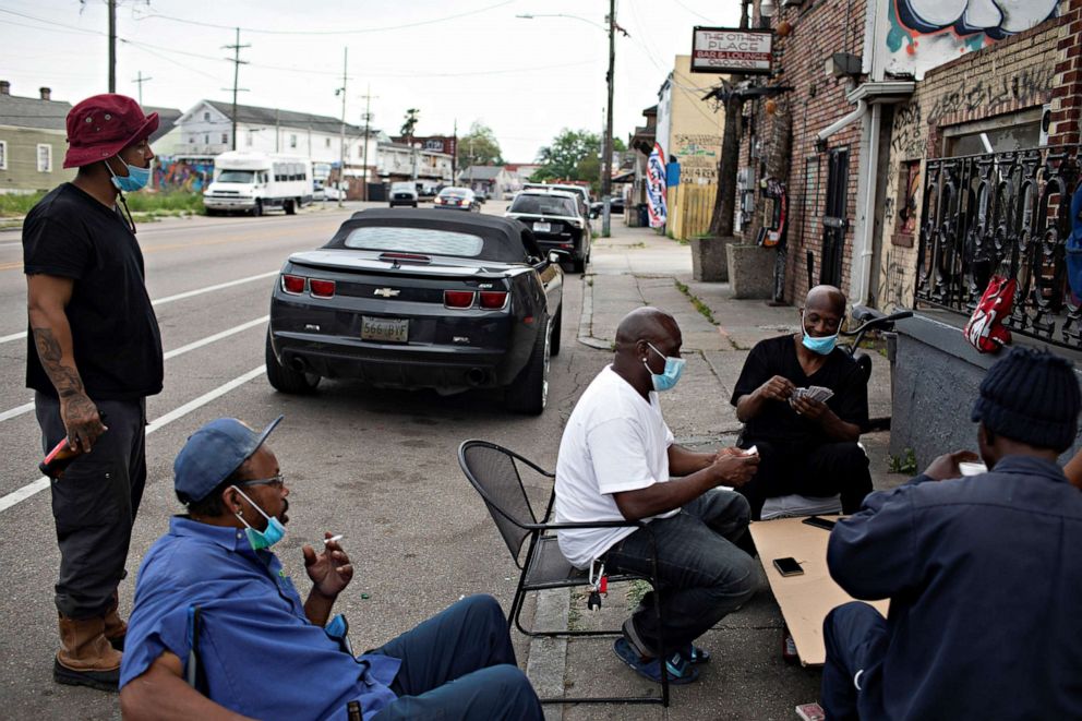 PHOTO: Richard Spot, left, and Keith Newsome, bottom left, watch as their friends Keith Gibson, and Mike Williams, play spades on St. Bernard Avenue in New Orleans, amid the COVID-19 outbreak pandemic, April 7, 2020.
