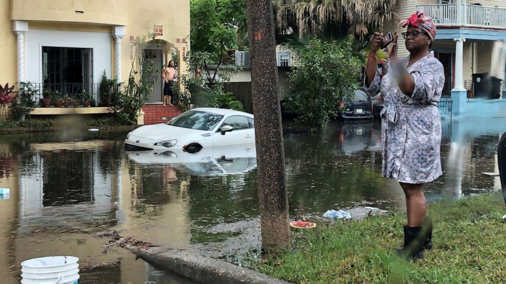 PHOTO: A woman stands photographing the scene in a flooded street in New Orleans, July 10, 2019.