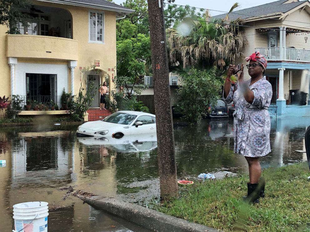 PHOTO: A woman stands photographing the scene in a flooded street in New Orleans,  July 10, 2019.