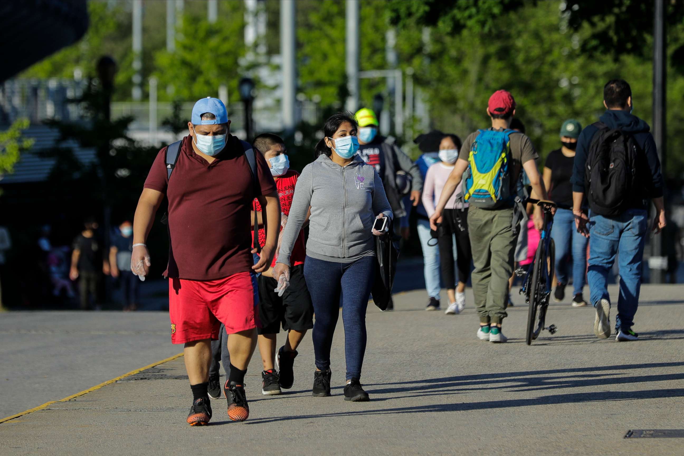 PHOTO: Pedestrians wear protective masks during the coronavirus pandemic as they enjoy warm weather in Flushing Meadows Corona Park, May 26, 2020, in Queens, New York.
