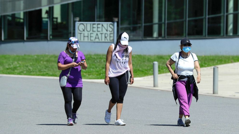 PHOTO: Women wear protective masks during the coronavirus pandemic as they pass the Queens Theatre, Tuesday, May 26, 2020, in the Queens borough of New York. (AP Photo/Frank Franklin II)