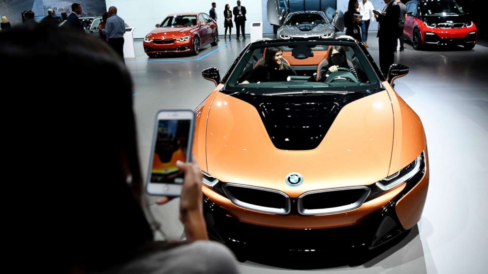 An attendee takes a photo of her friends in the 2019 BMW i8 Roadster during the show, March 28, 2018.
