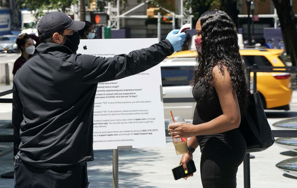 PHOTO: A woman has her temperature taken before she enters the  Apple  store on Fifth Avenue as New York City enters phase two of reopening on June 22, 2020. 