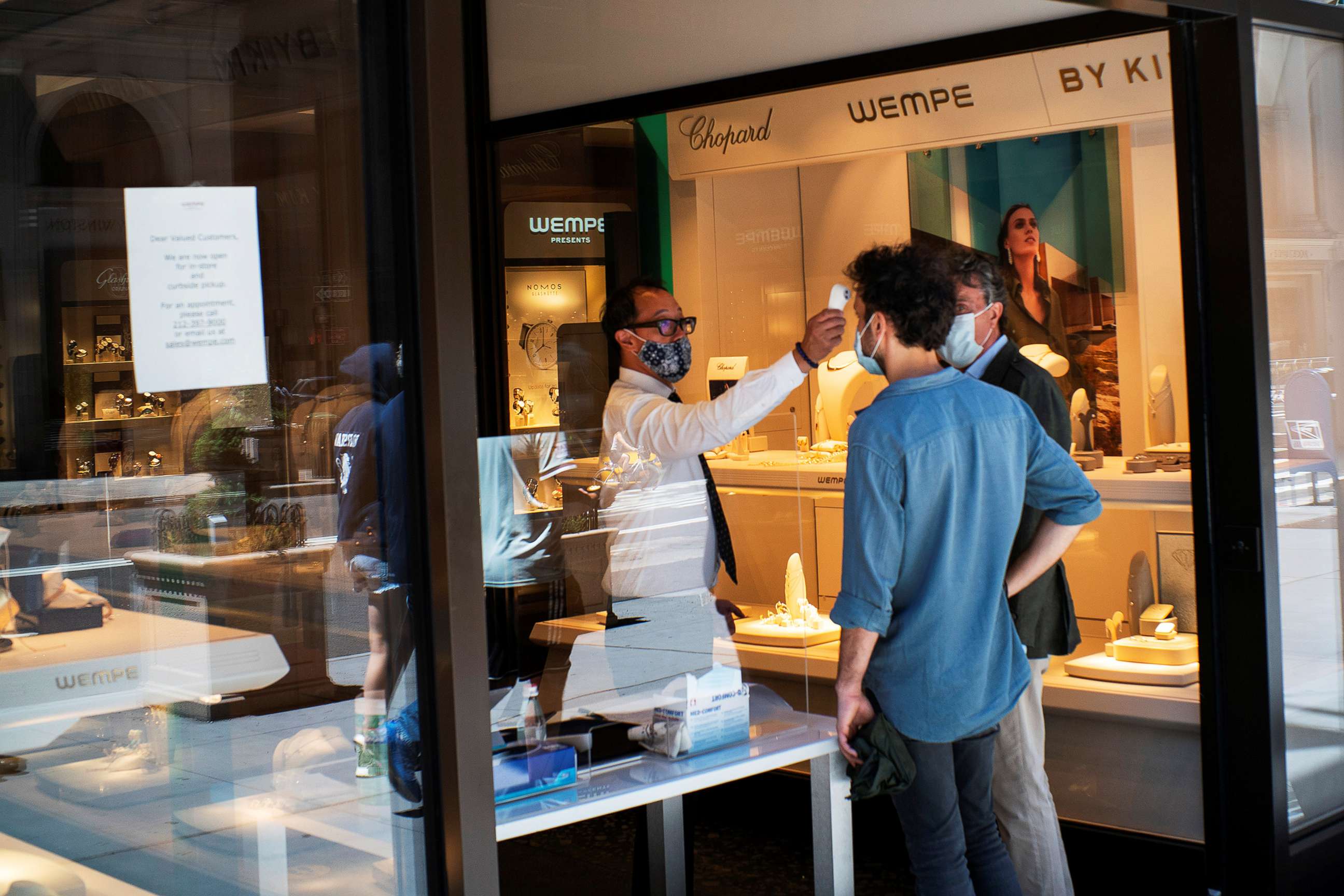 PHOTO: A worker checks the temperature of a client at a local store opened for pick up, as phase one of reopening after lockdown begins, during the outbreak of the coronavirus disease, in the Manhattan borough of New York, June 12, 2020.