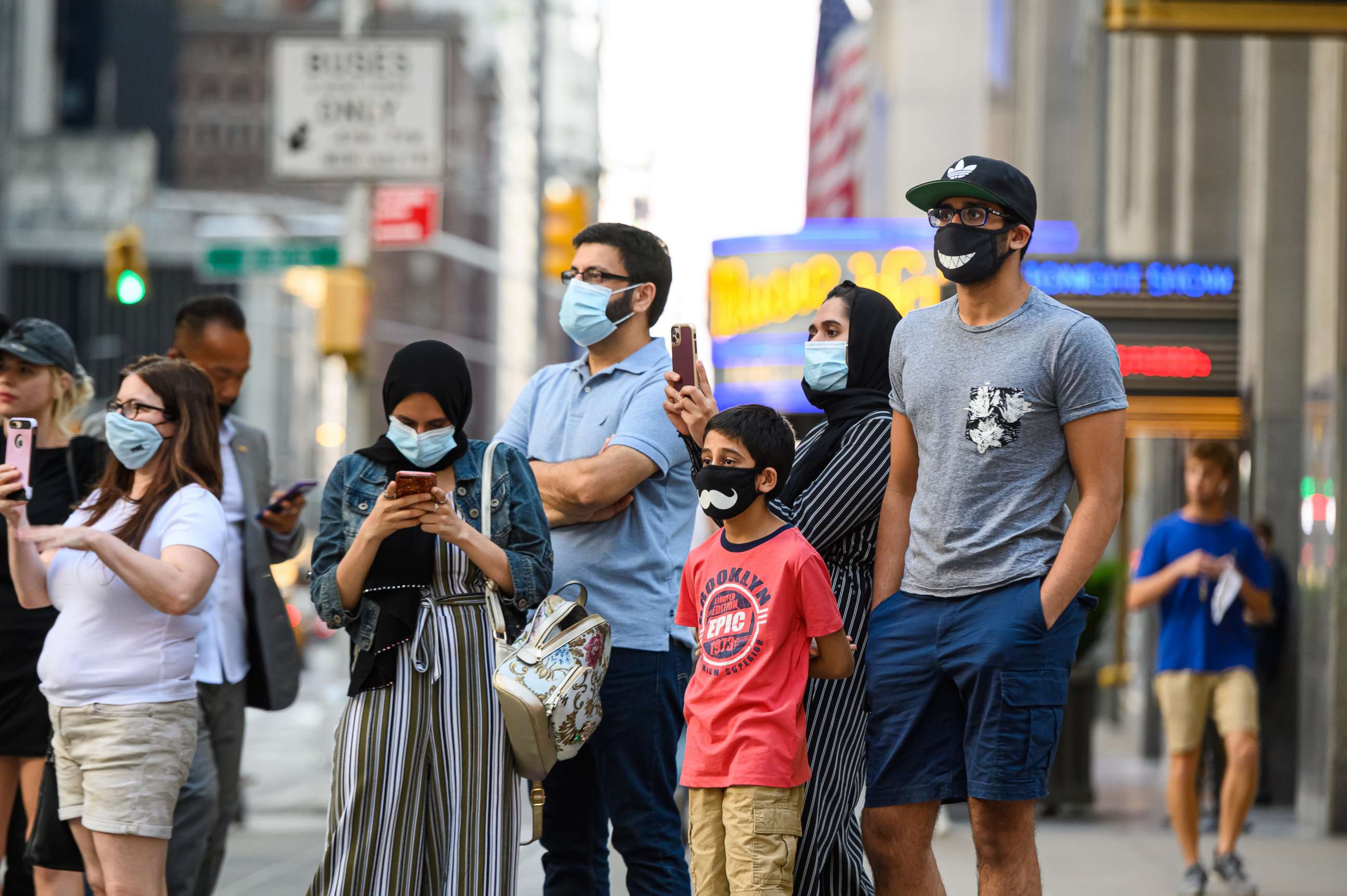PHOTO: People wear protective face masks outside Radio City Music Hall as New York City moves into Phase 3 of re-opening following restrictions imposed to curb the coronavirus pandemic on July 12, 2020.