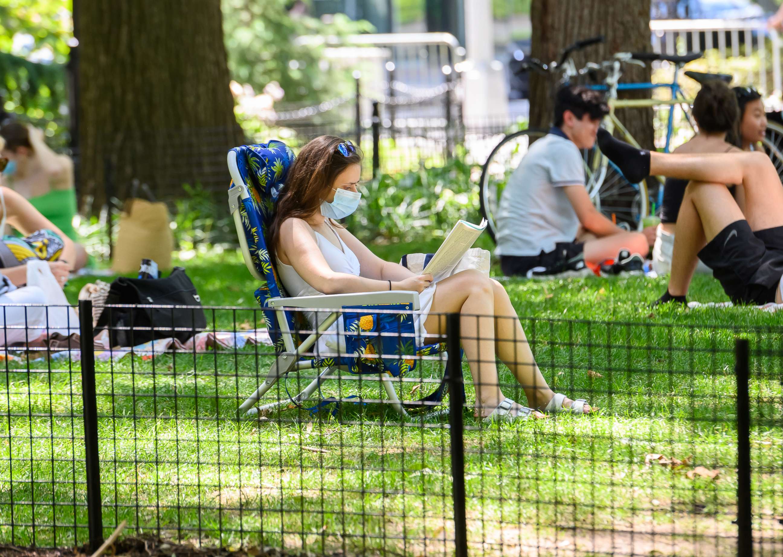 PHOTO: A person wears a protective face mask while reading a book in Washington Square Park as New York City moves into Phase 3 of re-opening following restrictions imposed to curb the coronavirus pandemic on July 12, 2020.