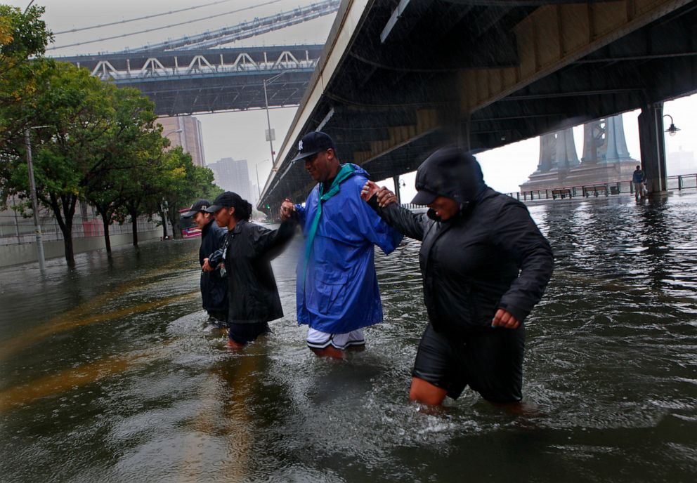 PHOTO: People walk through a flooded section of lower Manhattan along the East River after Hurricane Irene in New York, Aug. 27, 2011.