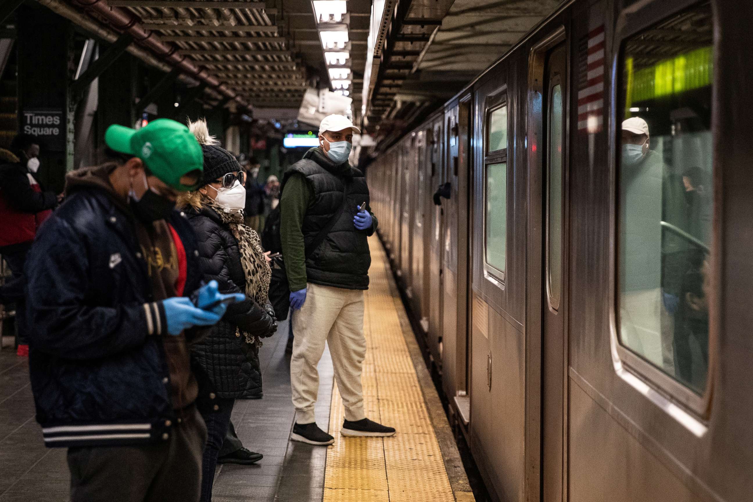 PHOTO: In this April 17, 2020, file photo, people stand on the platform in the Times Square subway station in New York.