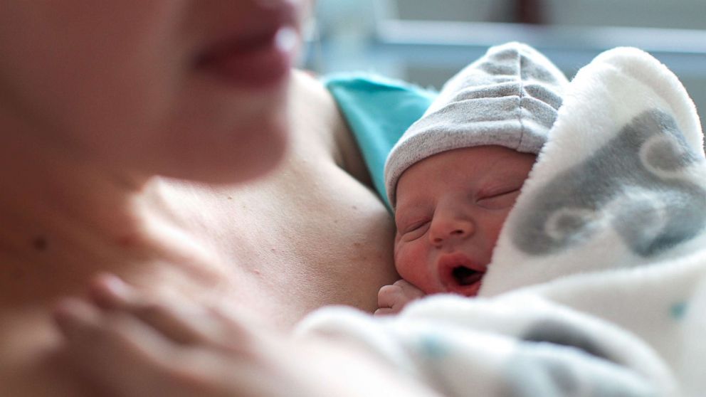 A newborn baby boy breastfeeding for the first time in hospital, directly after a cesarean section.