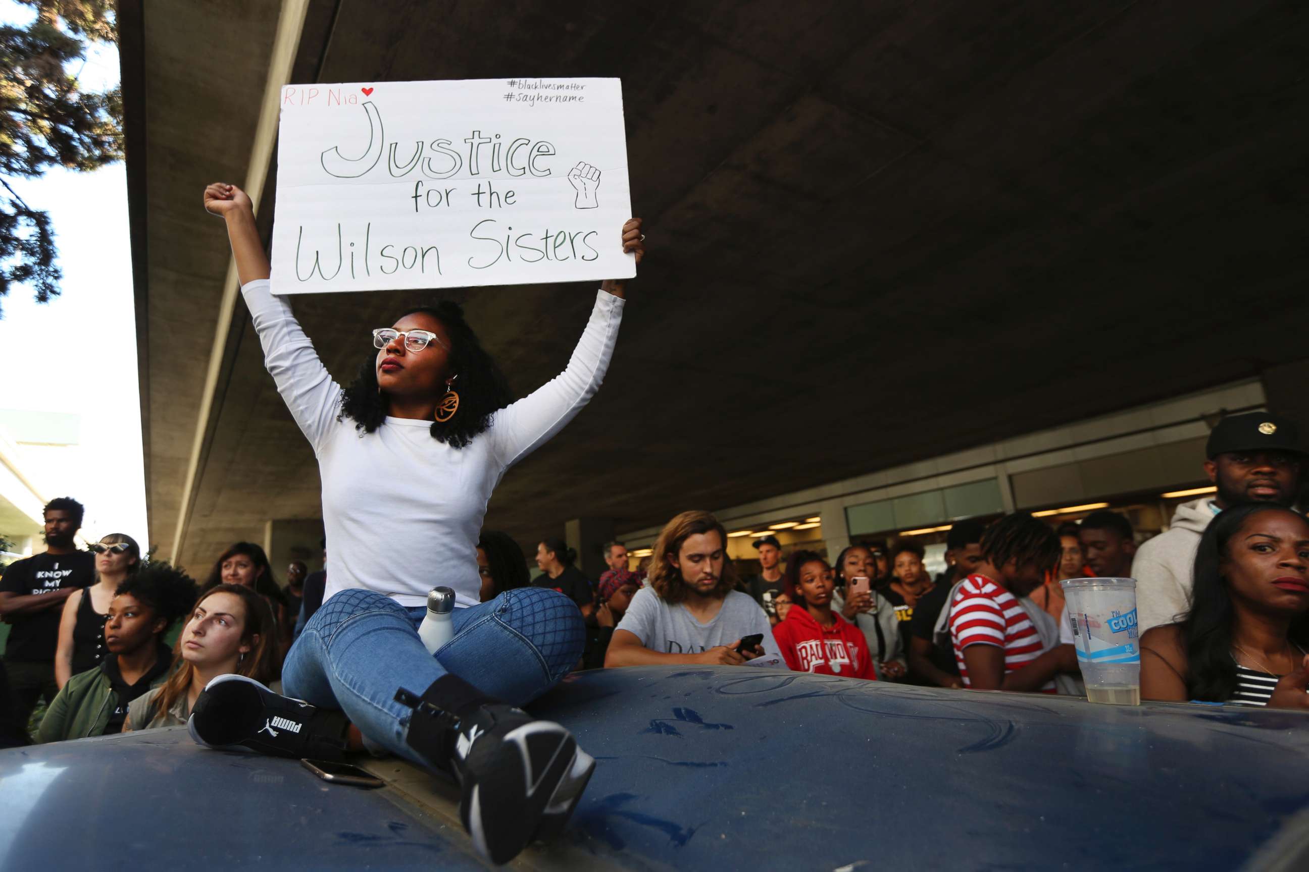 PHOTO: Jasmine Malone, 23, holds a sign at a vigil held for 18-year-old Nia Wilson, who was stabbed to death the previous night on July 23, 2018, at the MacArthur BART station in Oakland, Calif.