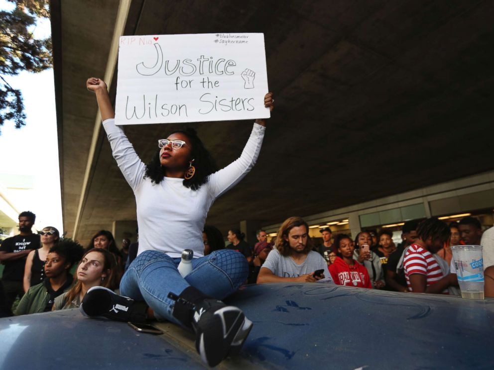 PHOTO: Jasmine Malone, 23, holds a sign at a vigil held for 18-year-old Nia Wilson, who was stabbed to death the previous night on July 23, 2018, at the MacArthur BART station in Oakland, Calif.