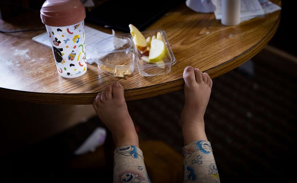 PHOTO: Audrey, 2, rests her feet on the table while eating a snack in the family's motel room, Jan. 6, 2022, in Richmond, Va.
