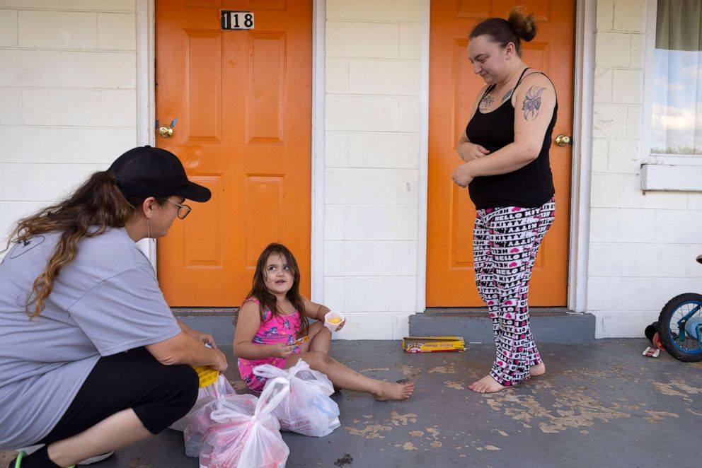 PHOTO: Jenny Varley, a volunteer with A Place of Miracles Cafe, a food bank serving families living in hotels in the area, drops off grocery items to NyAnna and her mother Nicki Schools, right, on Sept. 10, 2021, in Richmond, Va.