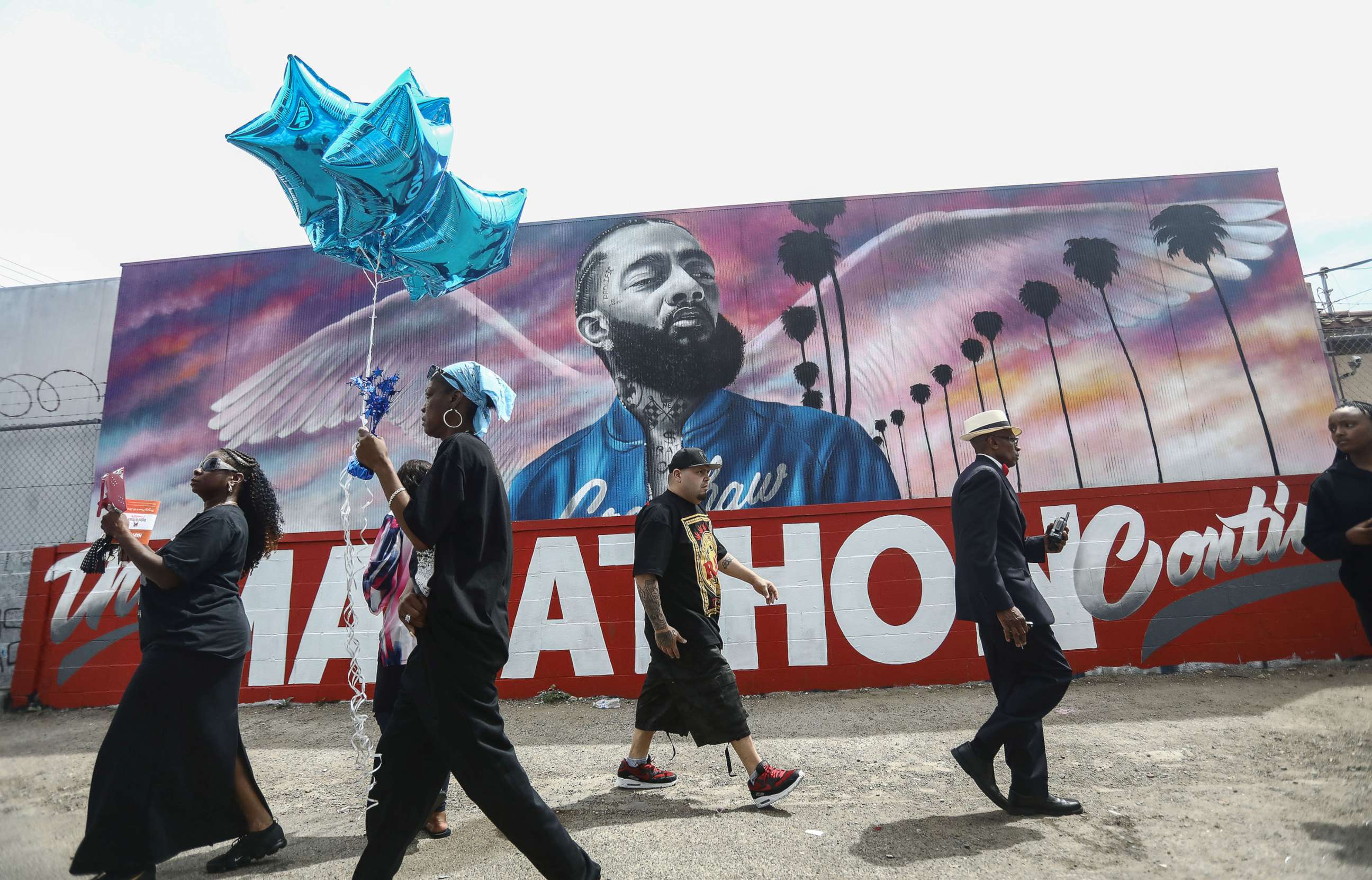 Fans walk as they wait outside The Marathon Clothing store for the funeral procession for slain rapper Nipsey Hussle, April 11, 2019, in Los Angeles.