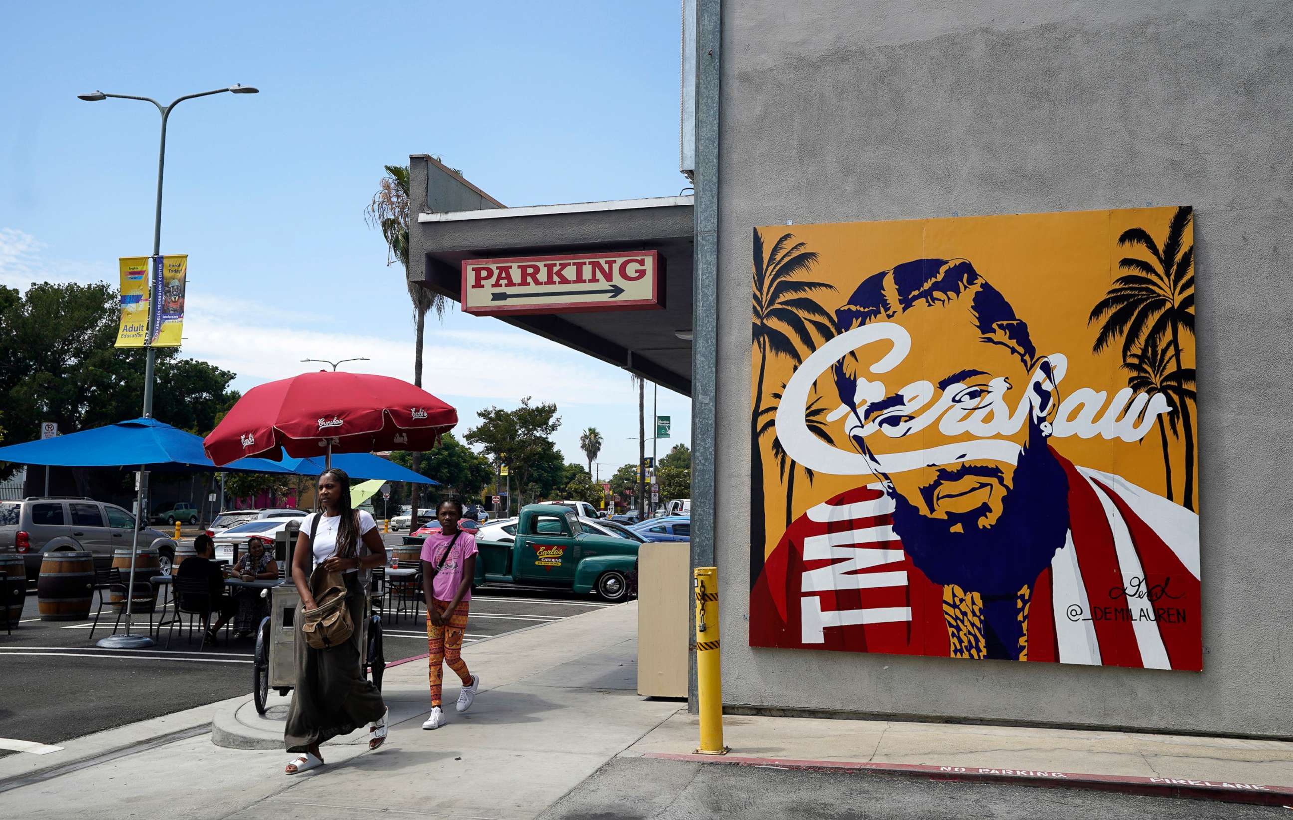 PHOTO: Pedestrians walk past a street mural of the late rapper Nipsey Hussle, June 30, 2022, in the Crenshaw district of Los Angeles.