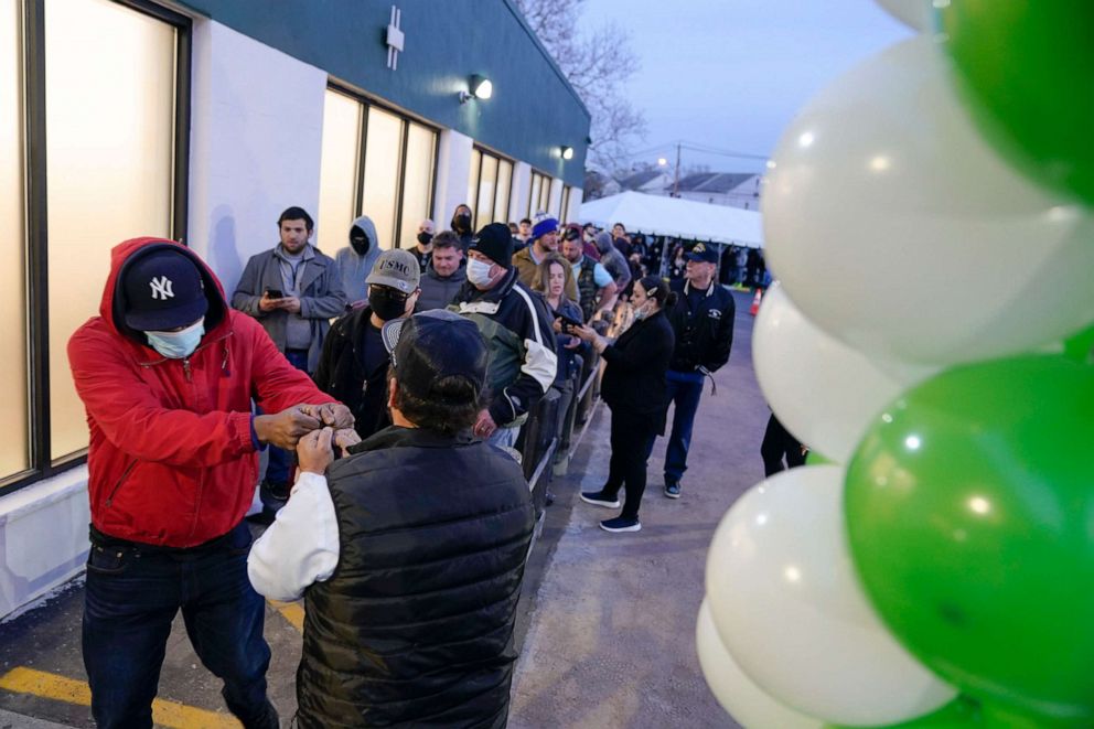 PHOTO: People give fist bumps as they enter a RISE dispensary in Bloomfield, N.J., April 21, 2022, on the first day of recreational sales of cannabis for adults 21 and older.