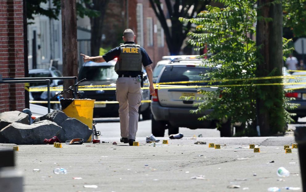 PHOTO: A police officer stands in a lot near evidence markers outside the warehouse building where the Art All Night Trenton 2018 festival was the scene of a shooting that resulted in numerous injuries and at least one death, June 17, 2018.