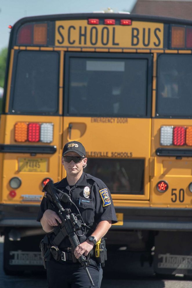 PHOTO: An armed police officers stands on the scene outside Noblesville High School as evacuated middle school students wait on a bus after a shooting at Noblesville West Middle School on May 25, 2018 in Noblesville, Ind.