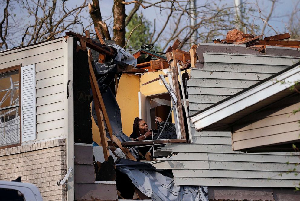 PHOTO: A woman collects belongings from a family members home after the roof was ripped off from a tornado on Oakview Drive in North Little Rock, Ark., on March 31, 2023.