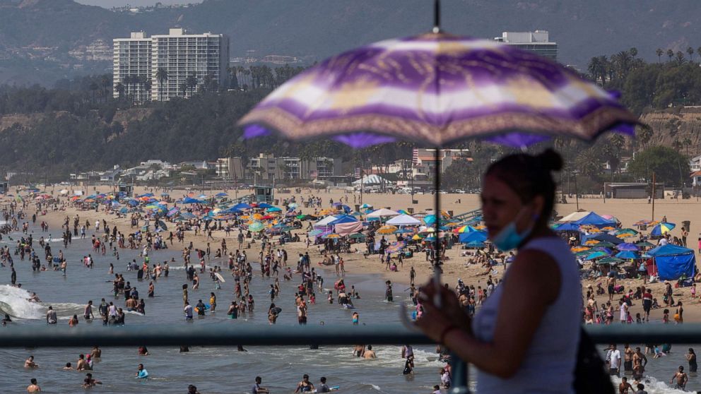 PHOTO: A woman uses an umbrella to protect herself from the sun at Santa Monica pier while people enjoy the beach on the second day of the Labor Day weekend amid a heatwave in Santa Monica, Caif., Sept. 6, 2020.