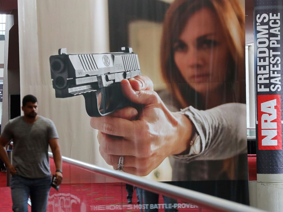 In this April 27, 2017 file photo, an attendee passes by a large banner advertising a handgun during the National Rifle Association convention at the Georgia World Congress Center in Atlanta.
