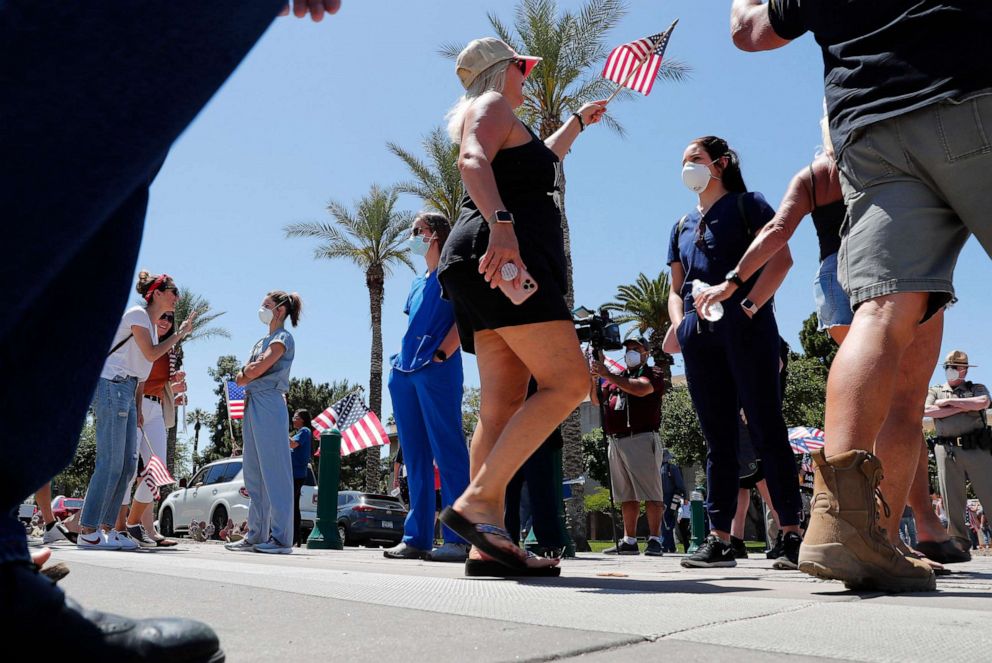 PHOTO: Health care workers stands in counter protest as people march towards the Arizona State Capitol in protest of Gov. Doug Ducey's stay-at-home order to combat the coronavirus, April 20, 2020, in Phoenix. 