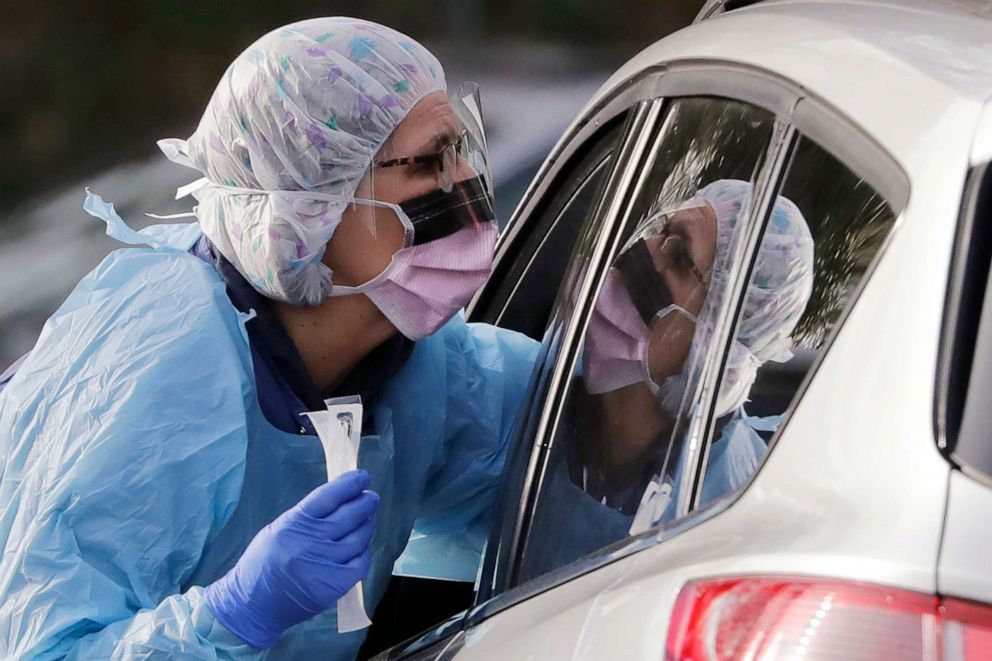 PHOTO: Laurie Kuypers, a registered nurse, reaches into a car to take a nasopharyngeal swab from a patient at a drive-through COVID-19 coronavirus testing station for University of Washington Medicine patients, March 17, 2020, in Seattle.