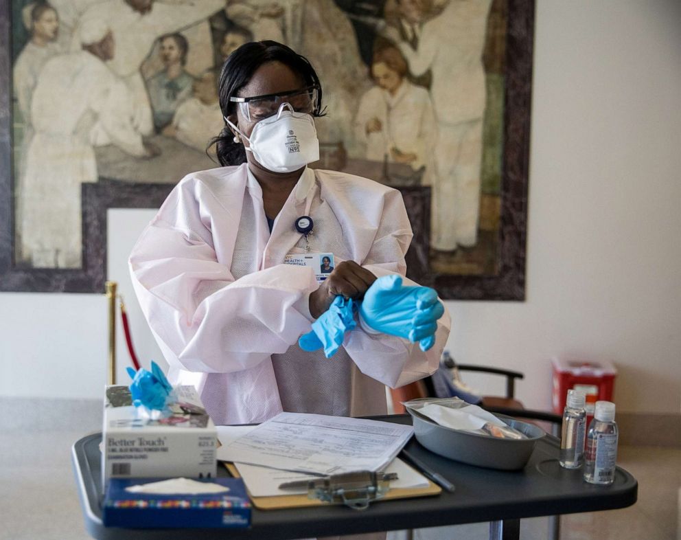 PHOTO: A nurse wearing a protective mask puts on a glove during the coronavirus disease (COVID-19) pandemic, at NYC Health + Hospitals Harlem Hospital in New York, Feb. 25, 2021.