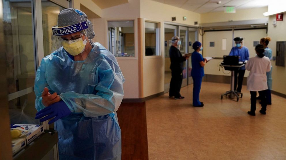 PHOTO: Registered nurse Merri Lynn Anderson puts on her personal protective equipment (PPE) to check on her patient in a COVID-19 unit at St. Joseph Hospital Orange in Orange, California, on Jan. 7, 2021.