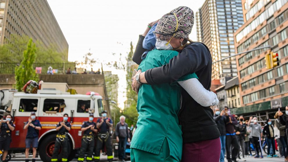 PHOTO: Medical workers hug outside NYU Langone Health Hospital as people applaud to show their gratitude to medical staff and essential workers during the pandemic on May 7, 2020, in New York City.