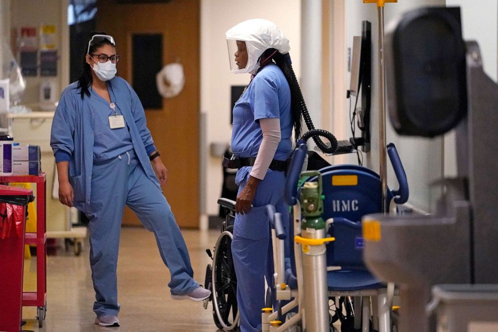 PHOTO: Two nurses talk in a hallway in the acute care unit, where about half the patients are COVID-19 positive or in quarantine after exposure, of Harborview Medical Center, Jan. 14, 2022, in Seattle.