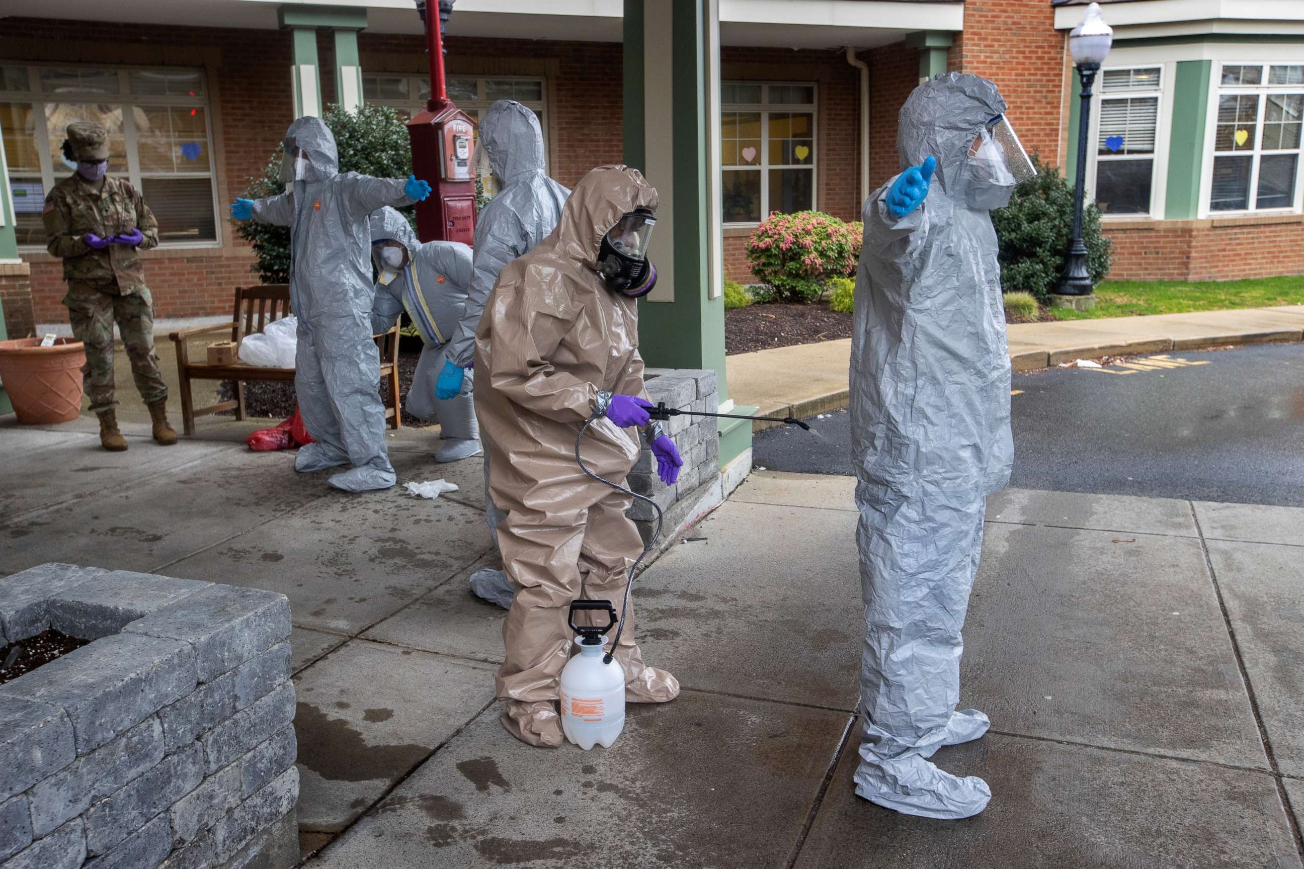 PHOTO: Members of the Massachusetts National Guard are sprayed down before removing their hazmat suits after leaving Alliance Health at Marina Bay in Quincy, MA on April 9, 2020. They were deployed to Quincy to assist nursing homes with COVID-19 testing.