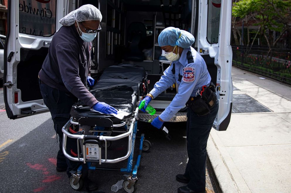 PHOTO: Two emergency medical staff of a private ambulance company sanitize a hospital gurney after they dropped off a patient at the Cobble Hill Health Center April 20, 2020 in the Brooklyn borough of New York City.