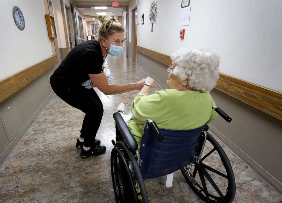 PHOTO: Rocky Knoll CNA Lori Ann Kisiolek bends down to greet resident Mary Bender, in Plymouth, Wis., Oct. 12, 2021.