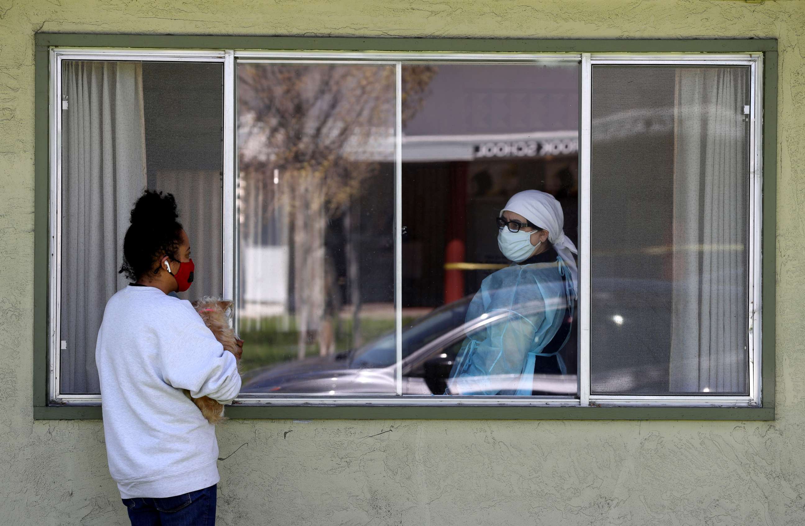 PHOTO: Adrina Rodriguez, talks with a nurse through a window as she visits her father who is a patient at the Gateway Care and Rehabilitation Center that has tested negative for COVID-19, April 14, 2020, in Hayward, California.