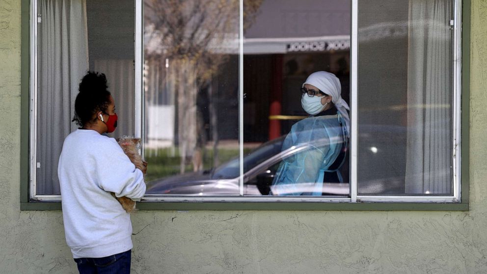 PHOTO: Adrina Rodriguez, talks with a nurse through a window as she visits her father who is a patient at the Gateway Care and Rehabilitation Center that has tested negative for COVID-19, April 14, 2020, in Hayward, California.