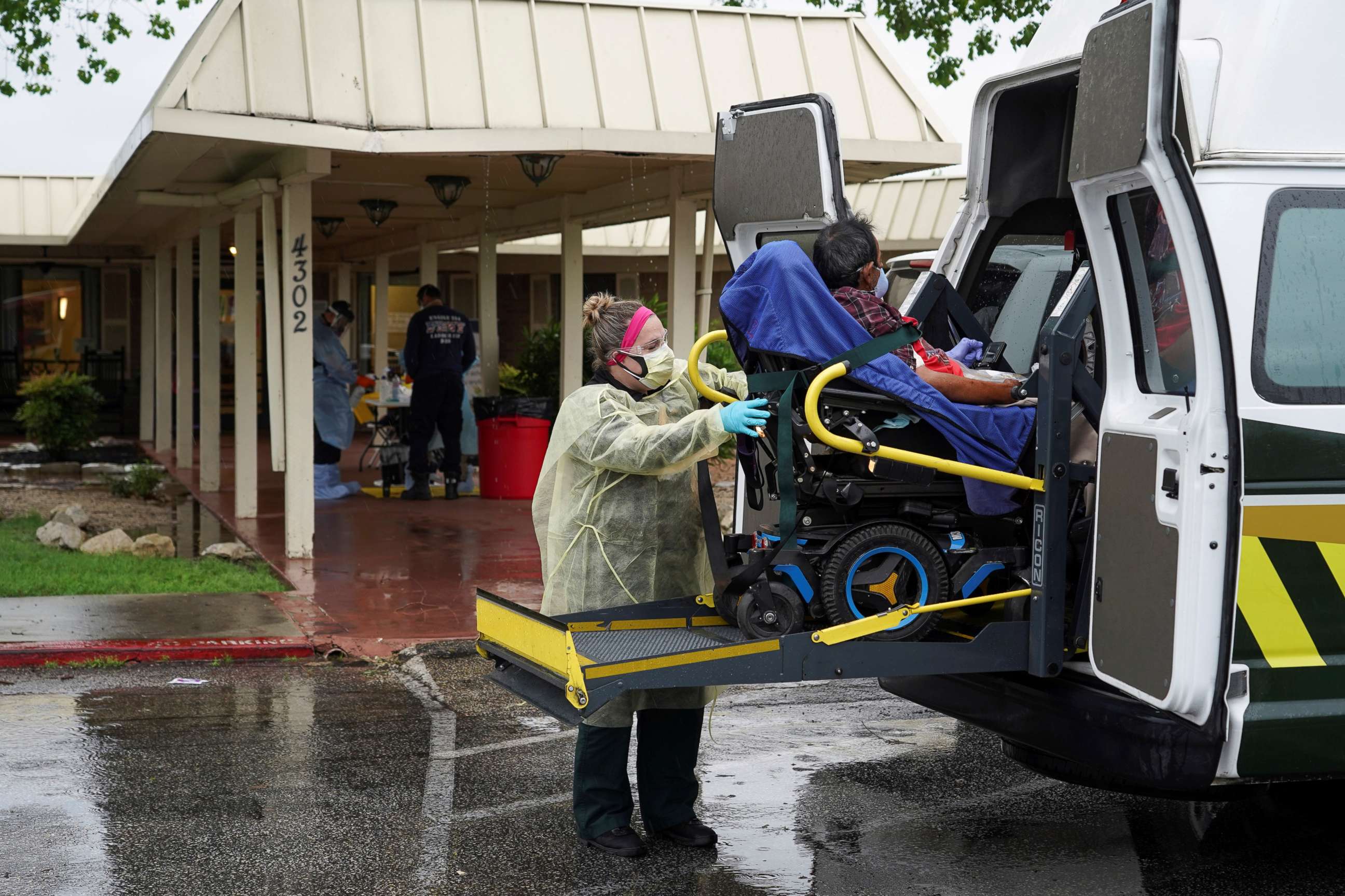 PHOTO: A healthcare worker in a protective suits helps an elderly person to get off an ambulance on April 4, 2020.