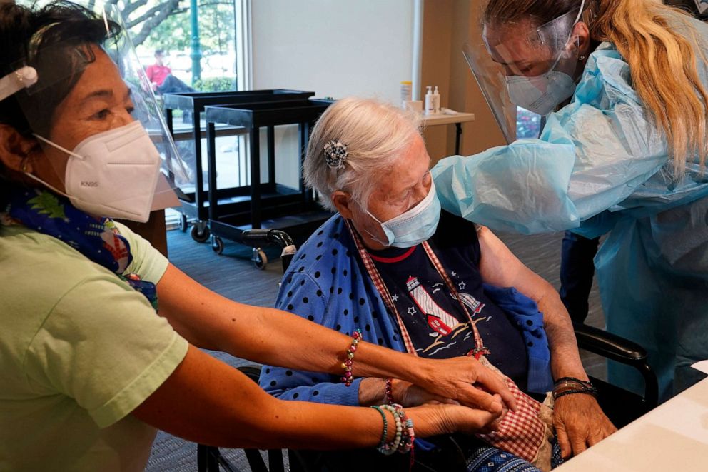 PHOTO: Patricia Wasseman, holds Hermina Levin's hands as nurse Eva Diaz administers the Pfizer vaccine at John Knox Village, Dec. 16, 2020, in Pompano Beach, Fla.