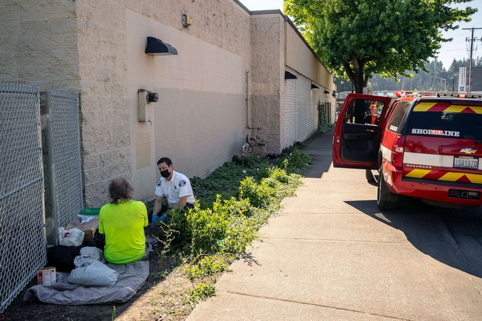 PHOTO: Gabe DeBay, Medical Services Officer with the Shoreline Fire Department, checks on a homeless man during the hottest part of the day, July 26, 2022 in Shoreline, Wa. 