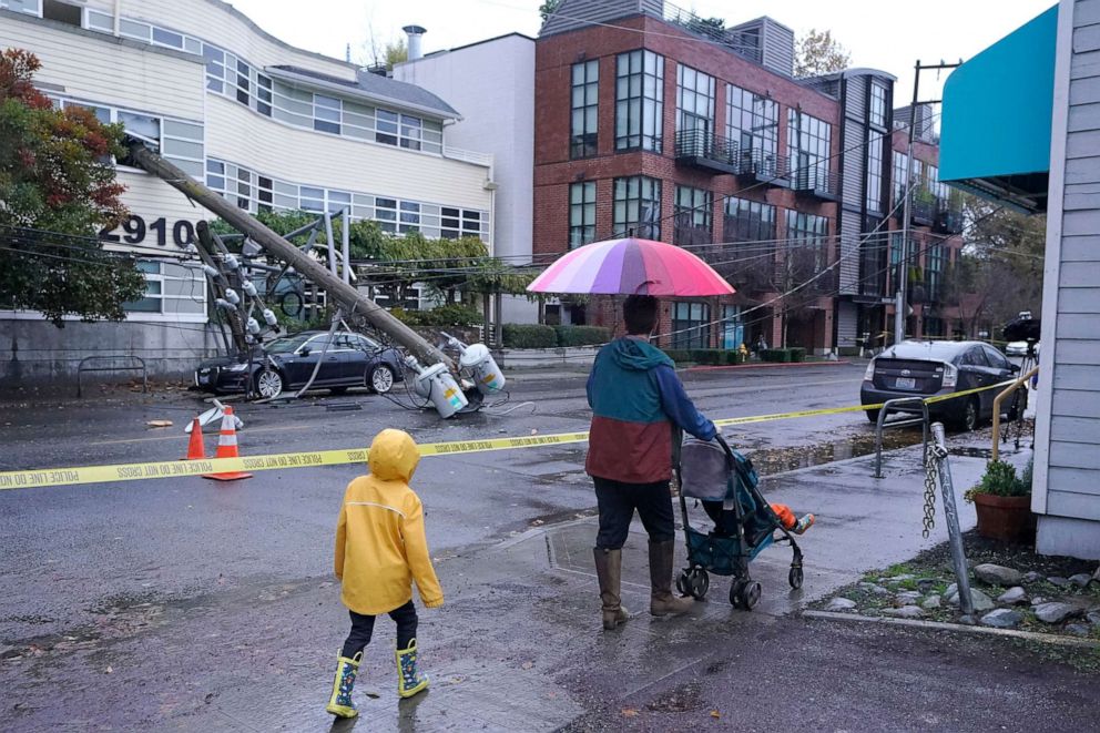 PHOTO: People walk past a downed power pole blocking a street in Seattle after it fell into an office building during a storm, Nov. 9, 2021.